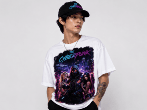 Portrait of a man wearing a white Cyberpunk graphic tee and a black cap with neon logo, posing against a light background.
