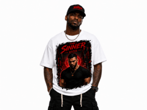 Man modeling a white graphic T-shirt featuring red and black artwork reading 'The Sinner 2130', with a black cap, chain, and tattoos in view.