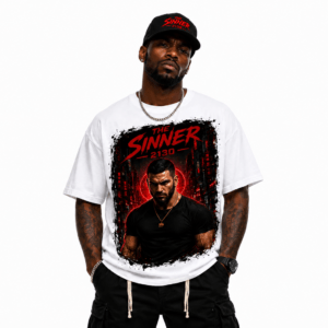 Man modeling a white graphic T-shirt featuring red and black artwork reading 'The Sinner 2130', with a black cap, chain, and tattoos in view.